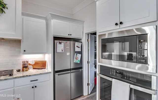 kitchen with tasteful backsplash, light stone counters, ornamental molding, stainless steel appliances, and white cabinets