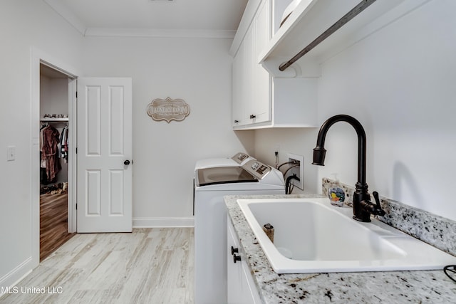 washroom featuring sink, light hardwood / wood-style flooring, washer and clothes dryer, cabinets, and ornamental molding