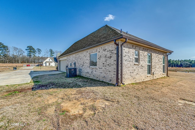 view of side of home with a yard, a garage, and central AC