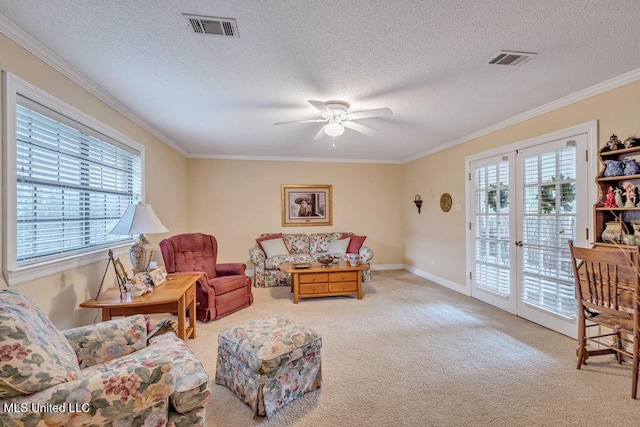 living area with a textured ceiling, french doors, ornamental molding, ceiling fan, and light colored carpet