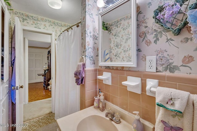 bathroom with parquet floors, tile walls, walk in shower, and sink