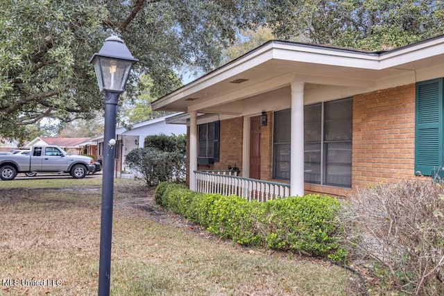 view of side of property featuring covered porch and a lawn