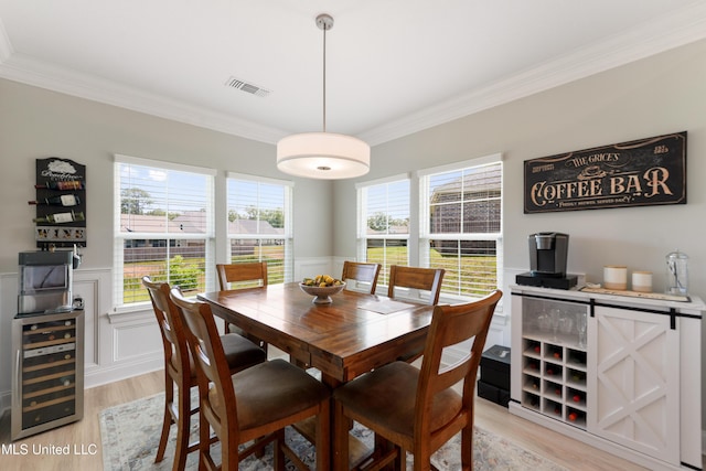 16872 W Landon Green Cir, Gulfport, MS 39503 - dining room with wine cooler, crown molding, a wainscoted wall, light wood-type flooring, and a decorative wall