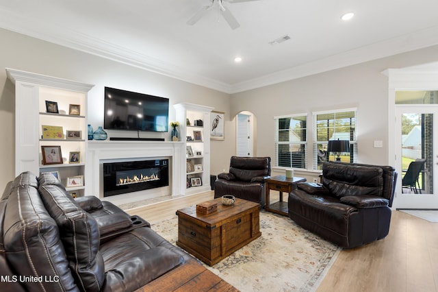 16872 W Landon Green Cir, Gulfport, MS 39503 - living room featuring a ceiling fan, light wood finished floors, arched walkways, crown molding, and a glass covered fireplace