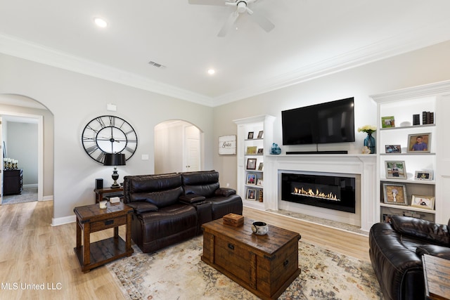 16872 W Landon Green Cir, Gulfport, MS 39503 - living area with arched walkways, a ceiling fan, light wood finished floors, crown molding, and a glass covered fireplace