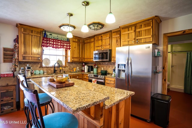 kitchen featuring a sink, backsplash, appliances with stainless steel finishes, light stone countertops, and hanging light fixtures