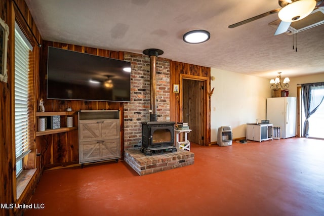 living area with a textured ceiling, concrete flooring, ceiling fan, and a wood stove