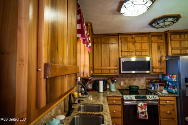 kitchen with brown cabinetry, tasteful backsplash, appliances with stainless steel finishes, and a sink