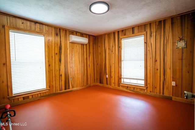 spare room with an AC wall unit, wooden walls, and a textured ceiling