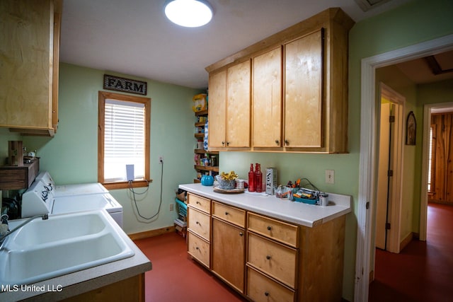 kitchen featuring a sink, baseboards, independent washer and dryer, and light countertops