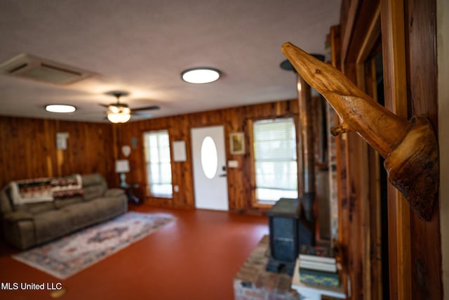 living room featuring visible vents, wood walls, and a ceiling fan