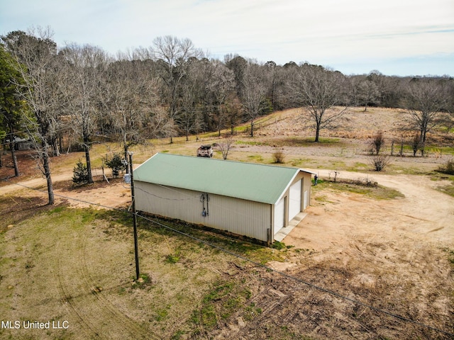 view of pole building with a rural view, driveway, and a wooded view