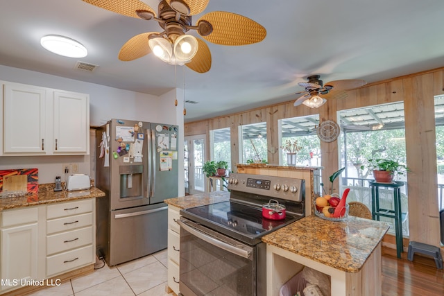 6132 Shawnee St, Kiln, MS 39556 - kitchen with appliances with stainless steel finishes, ceiling fan, white cabinets, light stone counters, and wood walls