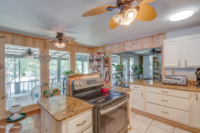 6132 Shawnee St, Kiln, MS 39556 - kitchen with stainless steel electric stove, ceiling fan, plenty of natural light, and white cabinetry