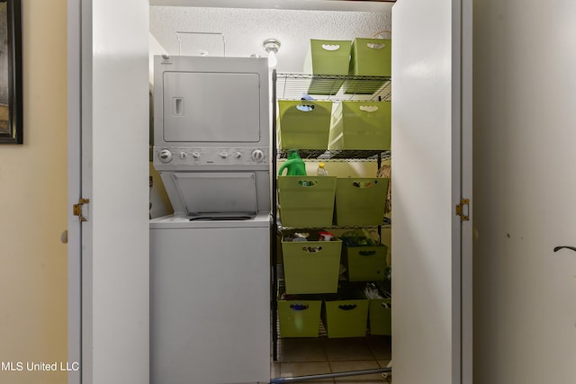 laundry area featuring stacked washer / dryer, a textured ceiling, and tile patterned flooring