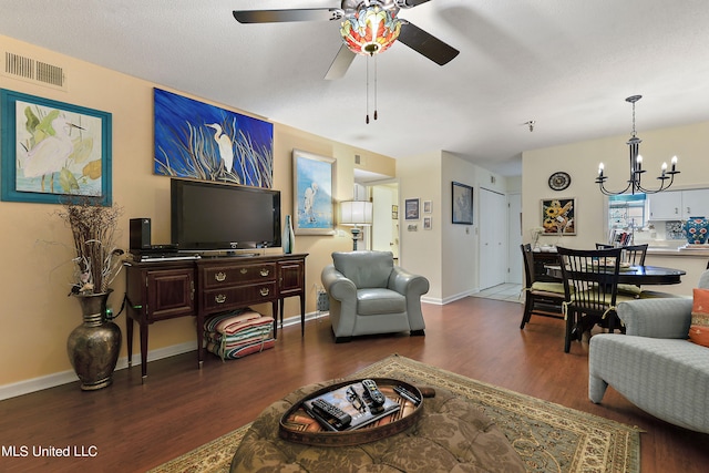 living room with ceiling fan with notable chandelier and dark hardwood / wood-style flooring