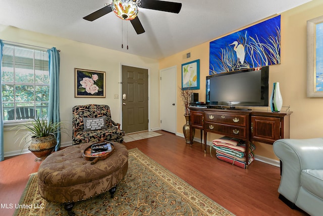 living room featuring a textured ceiling, wood-type flooring, and ceiling fan