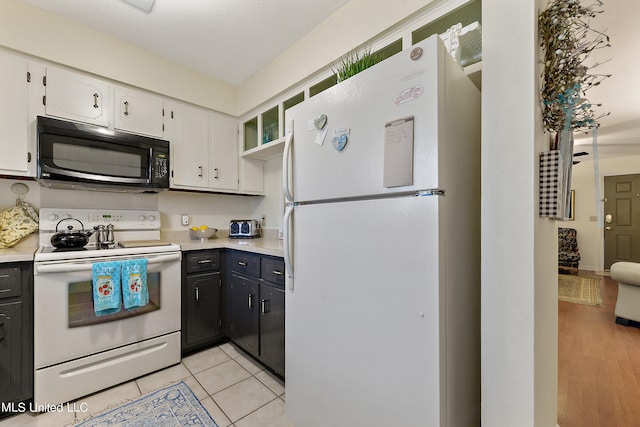 kitchen with a textured ceiling, white cabinetry, light wood-type flooring, and white appliances