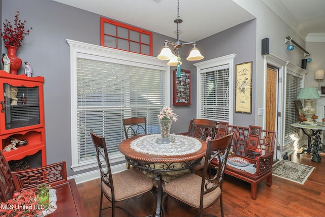 dining room with dark hardwood / wood-style floors, crown molding, and an inviting chandelier