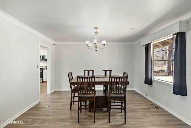 dining room featuring hardwood / wood-style floors, ornamental molding, and a chandelier