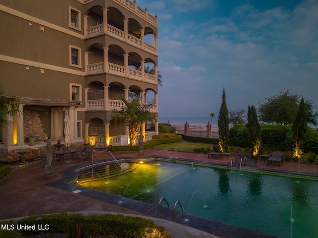 pool at dusk with a patio area