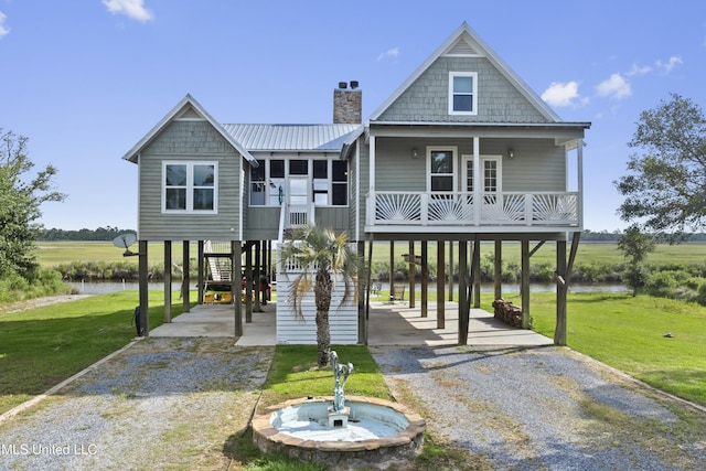 raised beach house featuring a chimney, driveway, a front lawn, and a carport