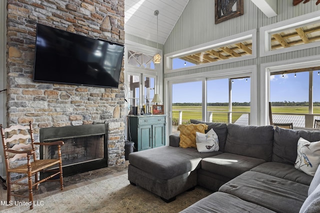 living area with a fireplace, a wealth of natural light, high vaulted ceiling, and wood finished floors