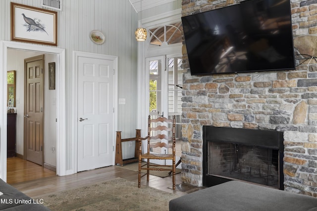 interior space featuring a wealth of natural light, a fireplace, visible vents, and wood finished floors