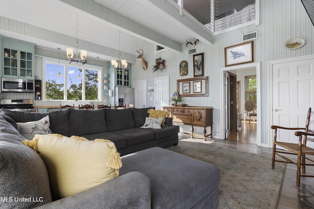 living room with beamed ceiling, a chandelier, visible vents, and wood finished floors