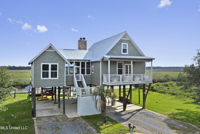rear view of property with a yard, dirt driveway, a carport, and a chimney