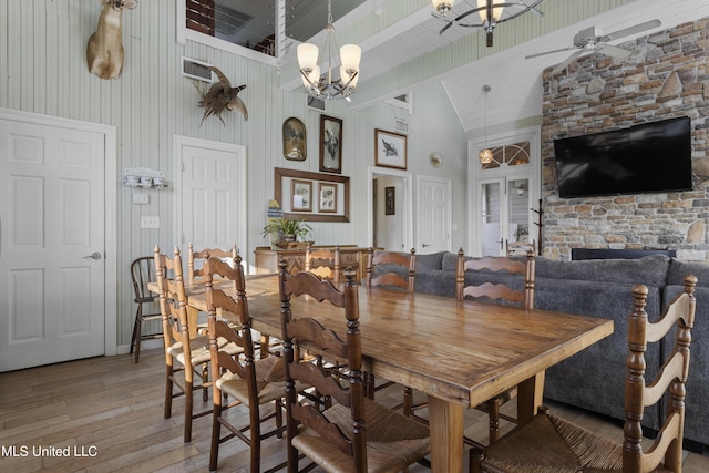 dining area featuring visible vents, ceiling fan with notable chandelier, wood-type flooring, and high vaulted ceiling