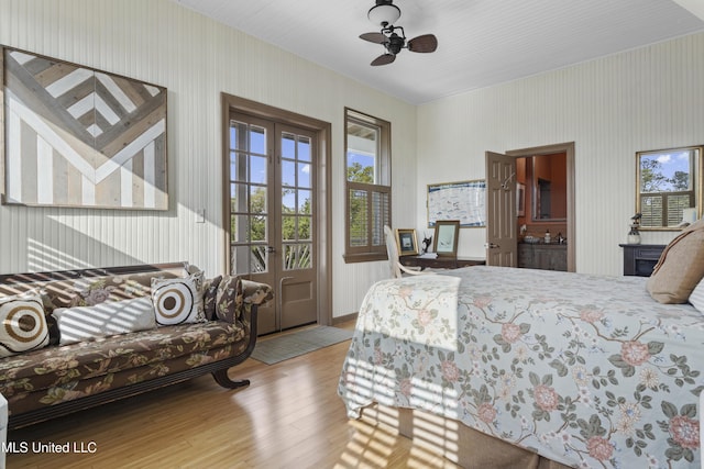 bedroom with access to exterior, wallpapered walls, and wood finished floors