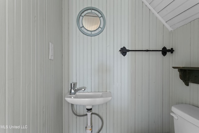 bathroom featuring toilet and wooden walls
