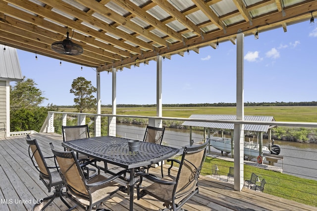 deck with a water view, a boat dock, outdoor dining area, and boat lift