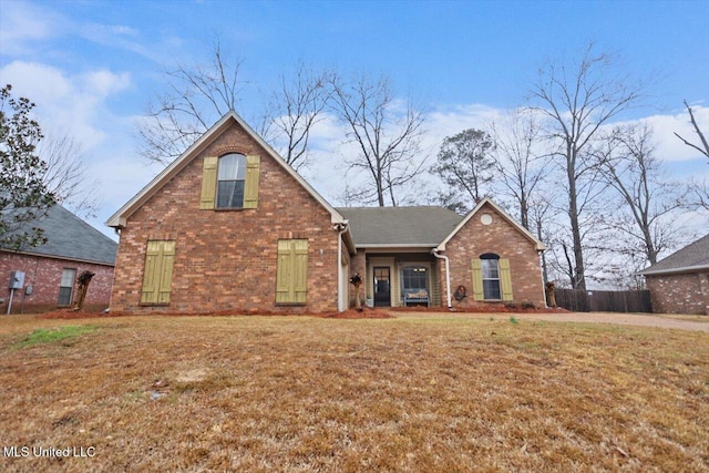 traditional-style home featuring brick siding, a front lawn, and fence