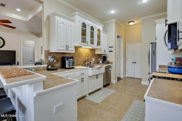 kitchen featuring light tile patterned flooring, a peninsula, white cabinetry, a ceiling fan, and appliances with stainless steel finishes