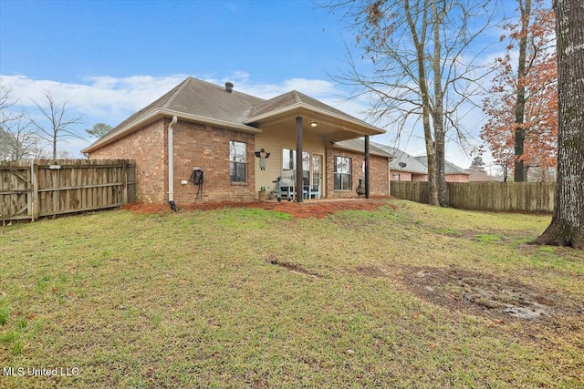 back of property with a yard, brick siding, and fence private yard