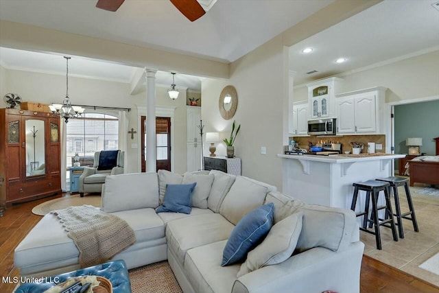 living room featuring recessed lighting, ornamental molding, wood finished floors, ornate columns, and ceiling fan with notable chandelier