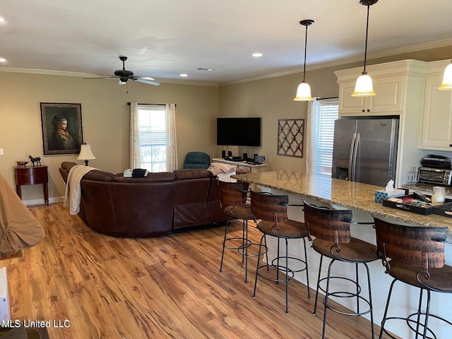 kitchen with light stone countertops, stainless steel refrigerator with ice dispenser, decorative light fixtures, and light hardwood / wood-style floors