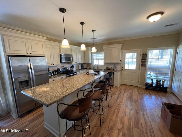 kitchen with light stone countertops, a center island, appliances with stainless steel finishes, and dark hardwood / wood-style floors