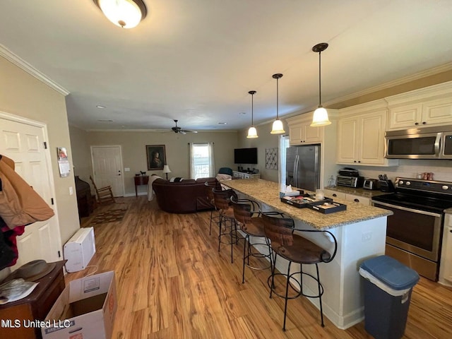 kitchen with a breakfast bar area, light stone countertops, light hardwood / wood-style flooring, pendant lighting, and stainless steel appliances