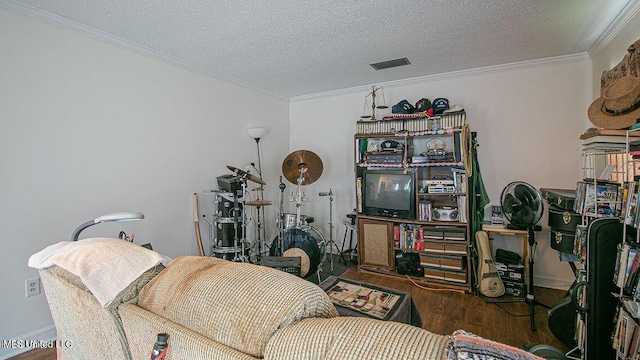 living area featuring a textured ceiling, visible vents, wood finished floors, and ornamental molding