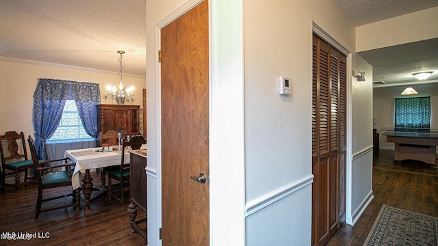 hall with an inviting chandelier, a textured ceiling, wood finished floors, and ornamental molding