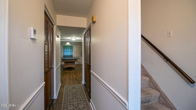 corridor with a textured ceiling and dark wood-style floors