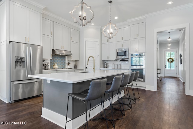 kitchen with an island with sink, stainless steel appliances, white cabinetry, and sink