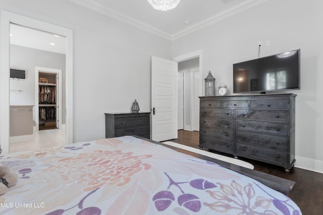 bedroom with hardwood / wood-style flooring, a walk in closet, and ornamental molding