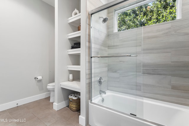 bathroom with toilet, tile patterned floors, and bath / shower combo with glass door