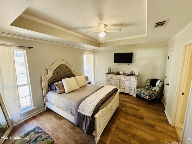 bedroom featuring ceiling fan, multiple windows, dark hardwood / wood-style flooring, and a raised ceiling