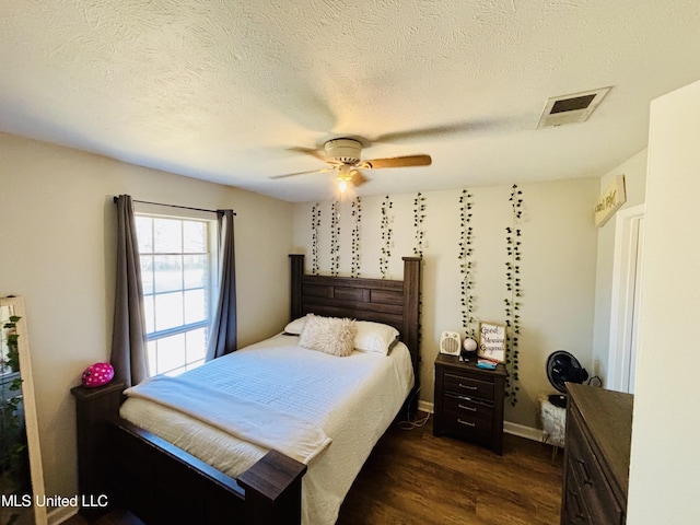 bedroom featuring dark wood-type flooring, a textured ceiling, and ceiling fan