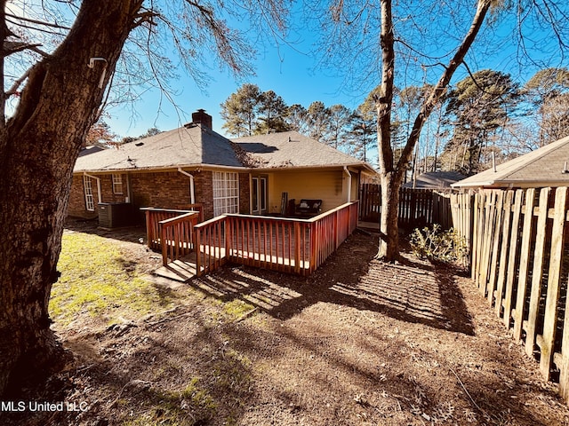 back of property featuring a wooden deck, a chimney, central AC, brick siding, and fence